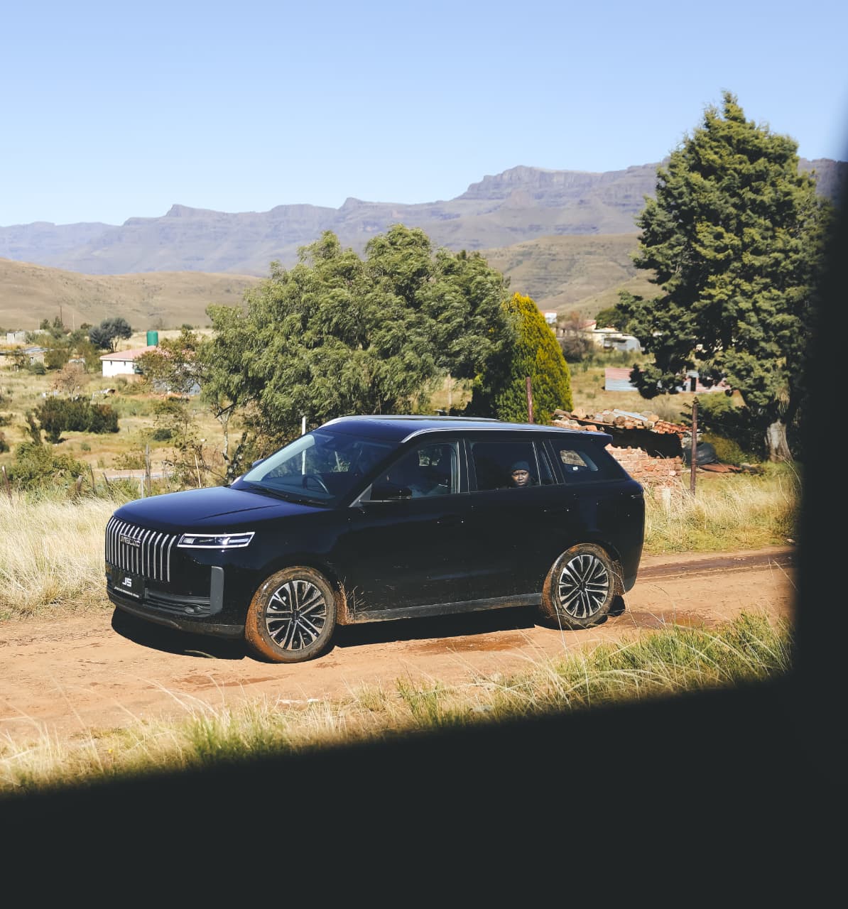 Black SUV on rural dirt road with mountains