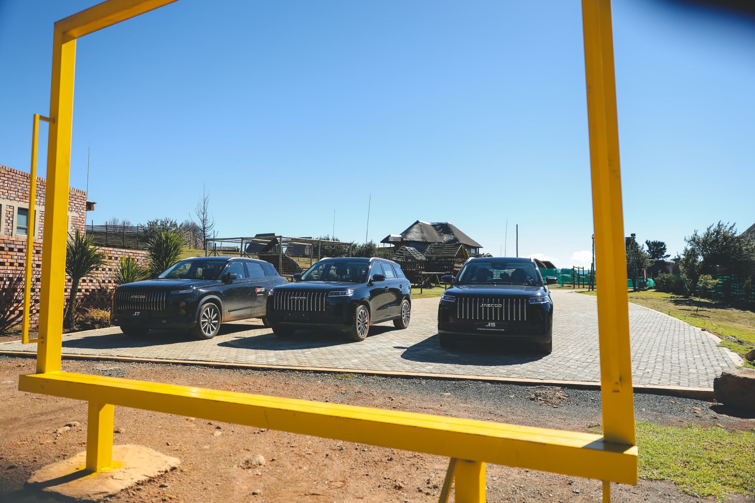 Three black SUVs parked under yellow frame