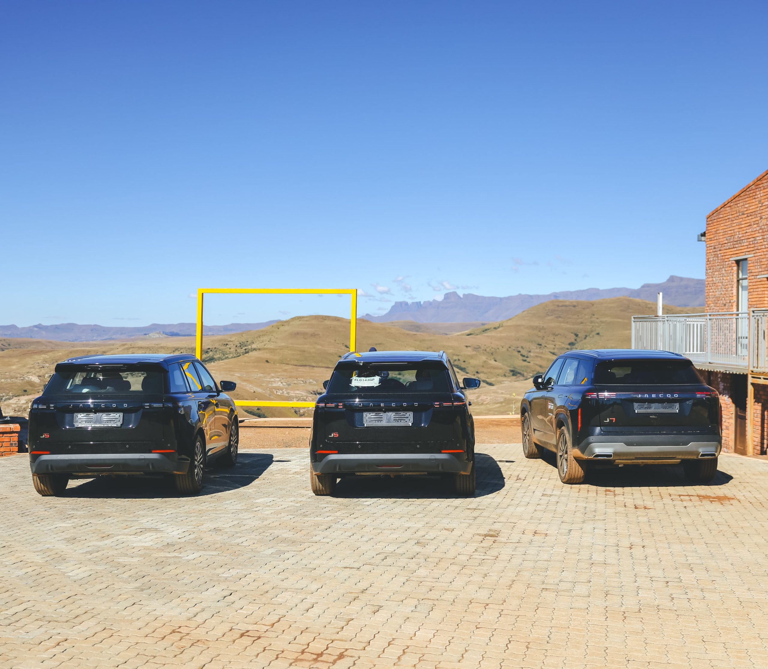 Three black SUVs overlooking mountain landscape