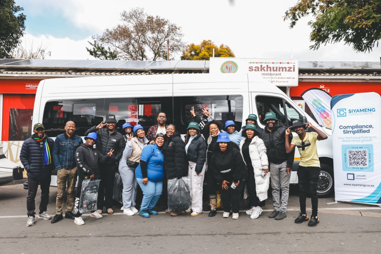 Group posing in front of branded minibus