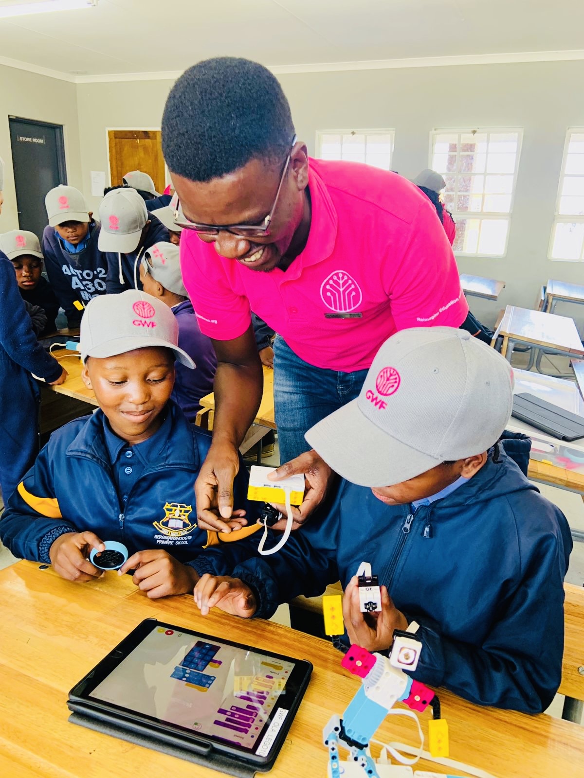 Teacher guiding learners with robotics and coding tablet