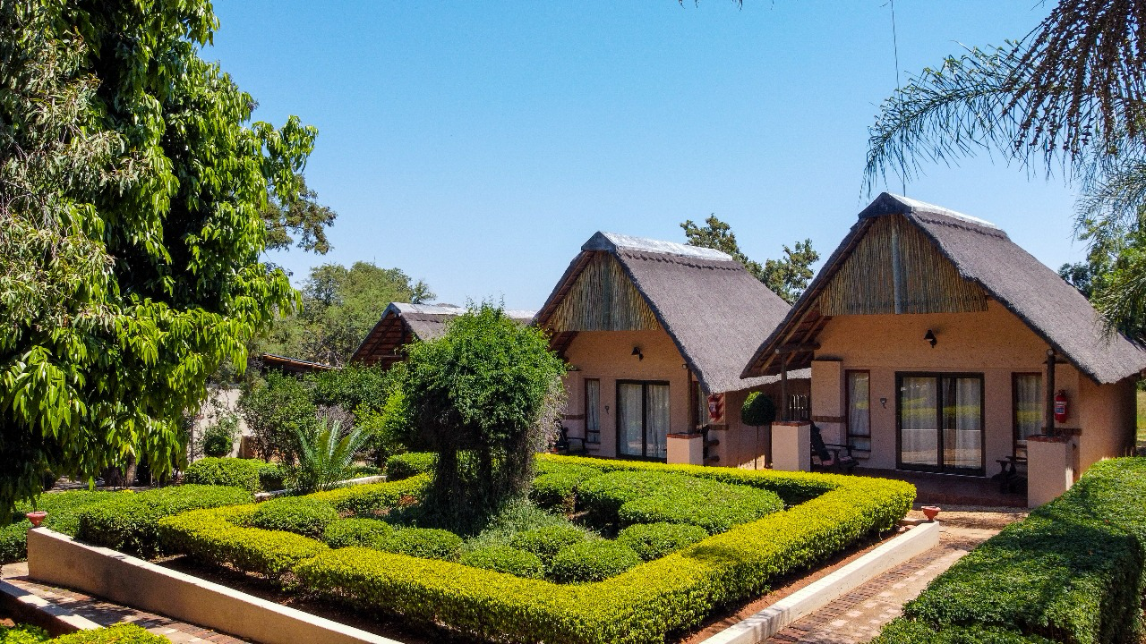 Thatched chalets beside manicured garden hedges