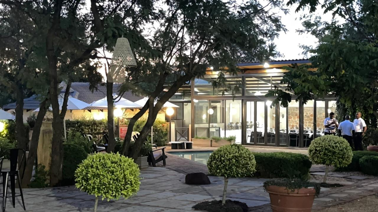 Garden courtyard with pool beside illuminated glass-walled venue