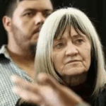 Older woman with long hair, serious expression.