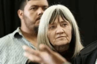 Older woman with long hair, serious expression.