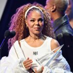 Person with trophy on stage, smiling brightly.