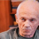 Older man gazing thoughtfully indoors.