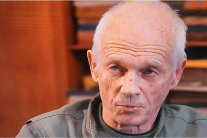 Older man gazing thoughtfully indoors.