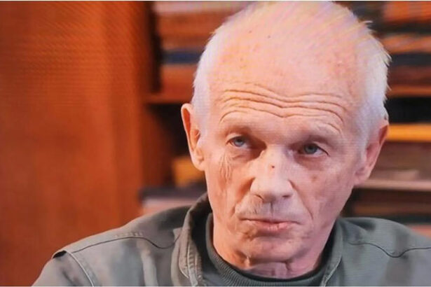 Older man gazing thoughtfully indoors.