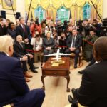 Conference room with people, cameras, model plane.