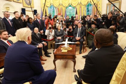 Conference room with people, cameras, model plane.
