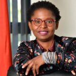 Woman with glasses, South African flag in background