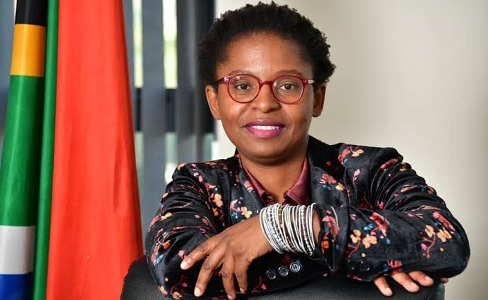 Woman with glasses, South African flag in background