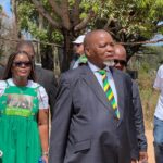 Group walking outdoors, man in striped tie leading.