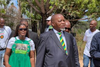 Group walking outdoors, man in striped tie leading.