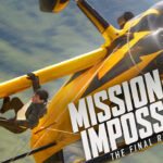 Person hanging on yellow plane in action scene.