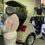 Forensic investigators examining car in laboratory.