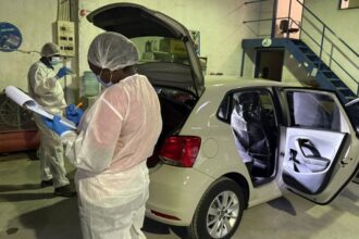 Forensic investigators examining car in laboratory.
