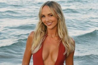 Smiling woman in red swimsuit at the beach.