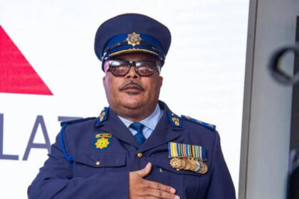 Police officer with medals salutes in formal uniform.