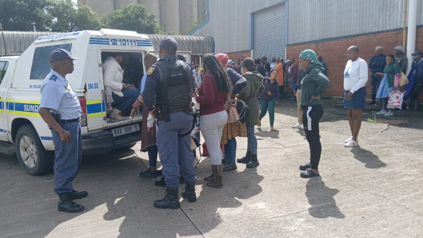 Police van with people detained outside building.