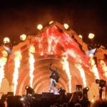 Performer on stage with fiery visual effects.