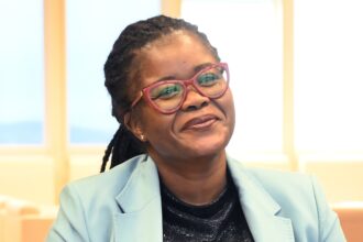 Smiling person wearing glasses and blue blazer.