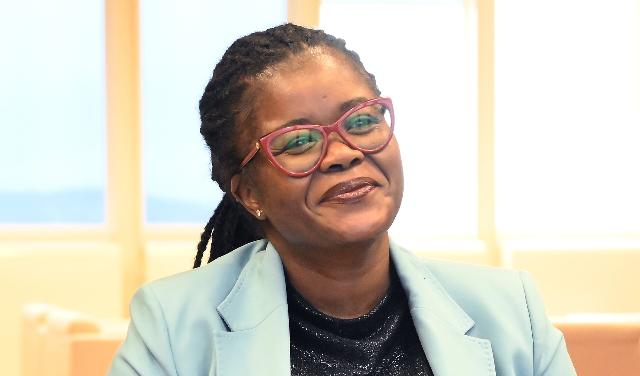 Smiling person wearing glasses and blue blazer.