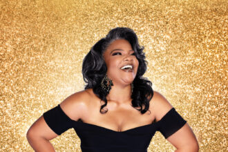 Smiling woman with curly hair against golden background.