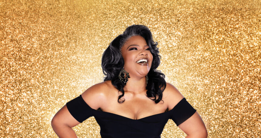 Smiling woman with curly hair against golden background.