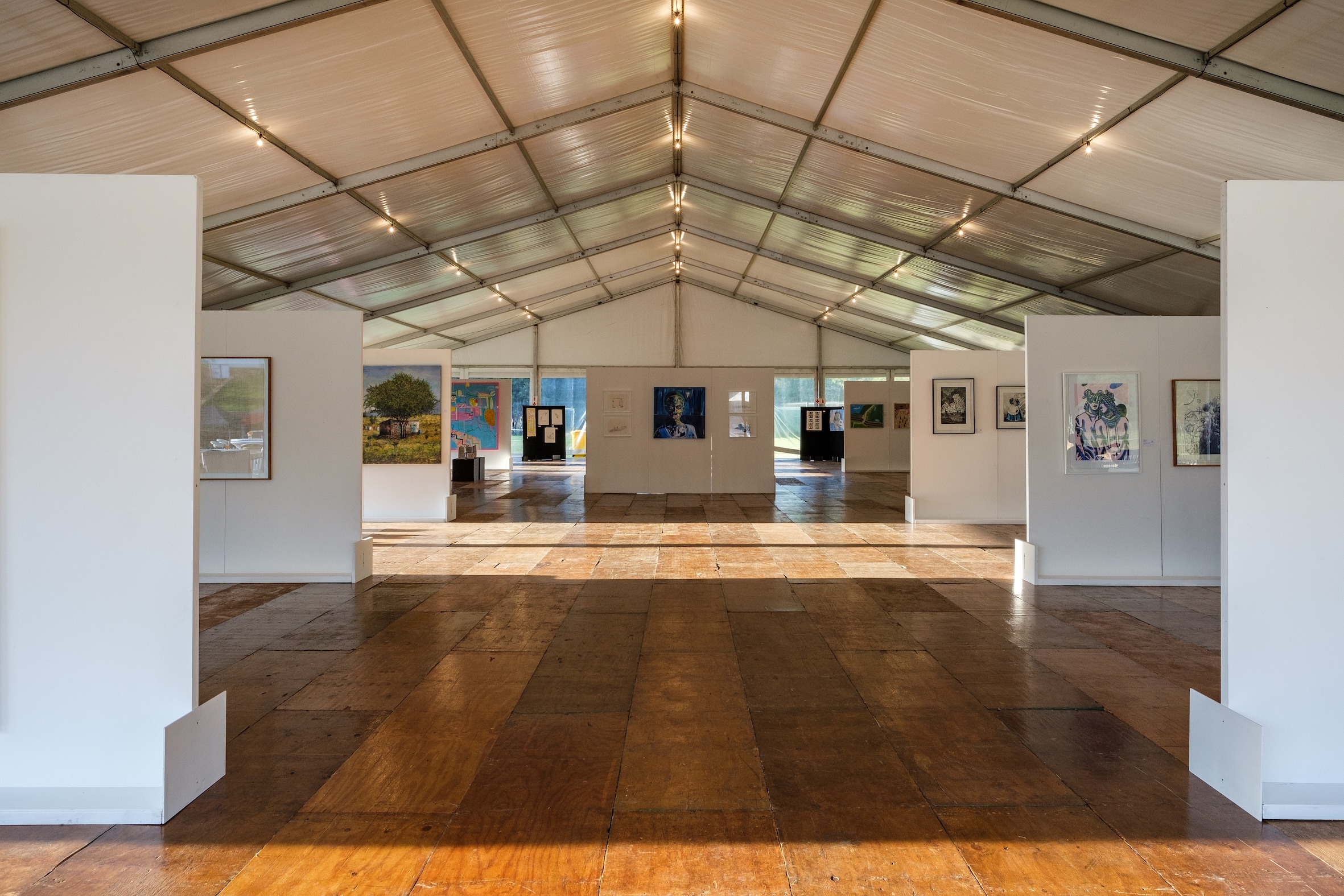 Spacious art exhibition hall displaying various artworks.