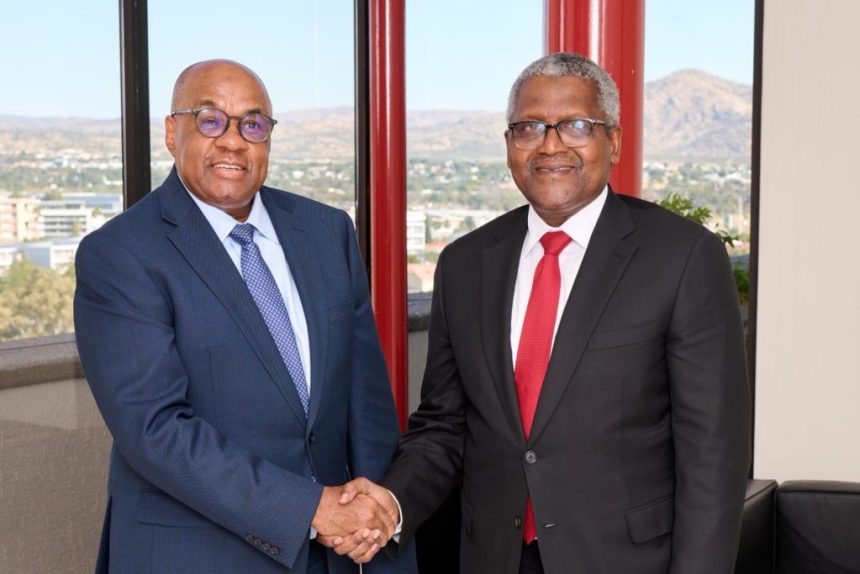 Two executives shaking hands in office setting.