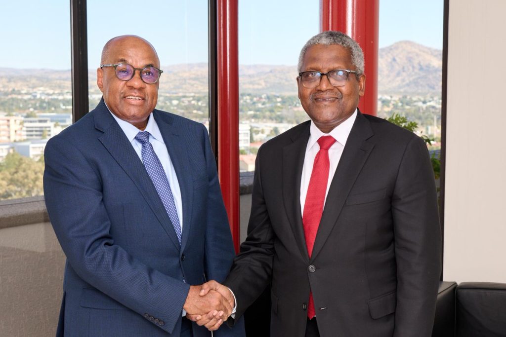 Two executives shaking hands in office setting.