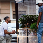Two men talking beside a street flower stand.