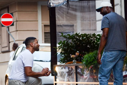 Two men talking beside a street flower stand.