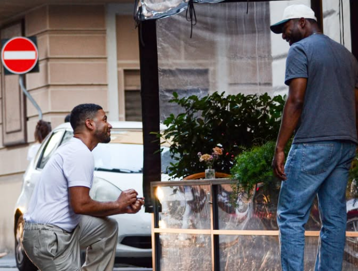 Two men talking beside a street flower stand.