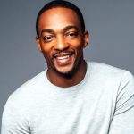 Smiling man in grey sweater, neutral background.