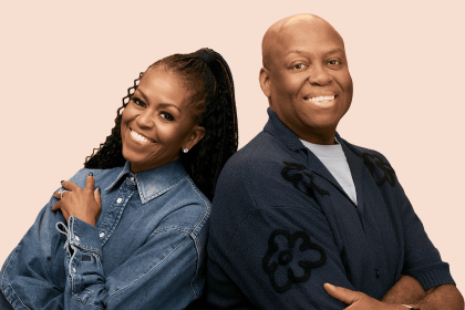 Two people smiling back-to-back, wearing denim and cardigan.