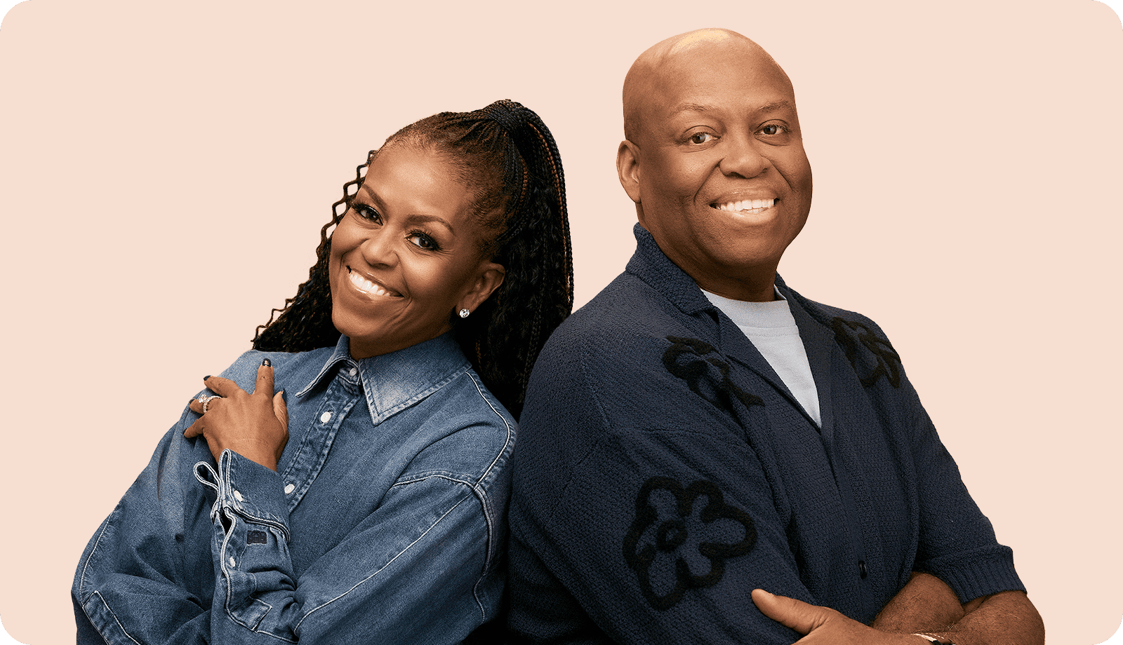Two people smiling back-to-back, wearing denim and cardigan.
