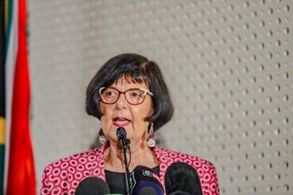 Woman speaking at a press conference podium.
