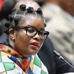 Person speaking at conference with colourful attire.