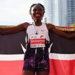 Runner celebrates with Kenyan flag and medal.