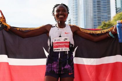 Runner celebrates with Kenyan flag and medal.
