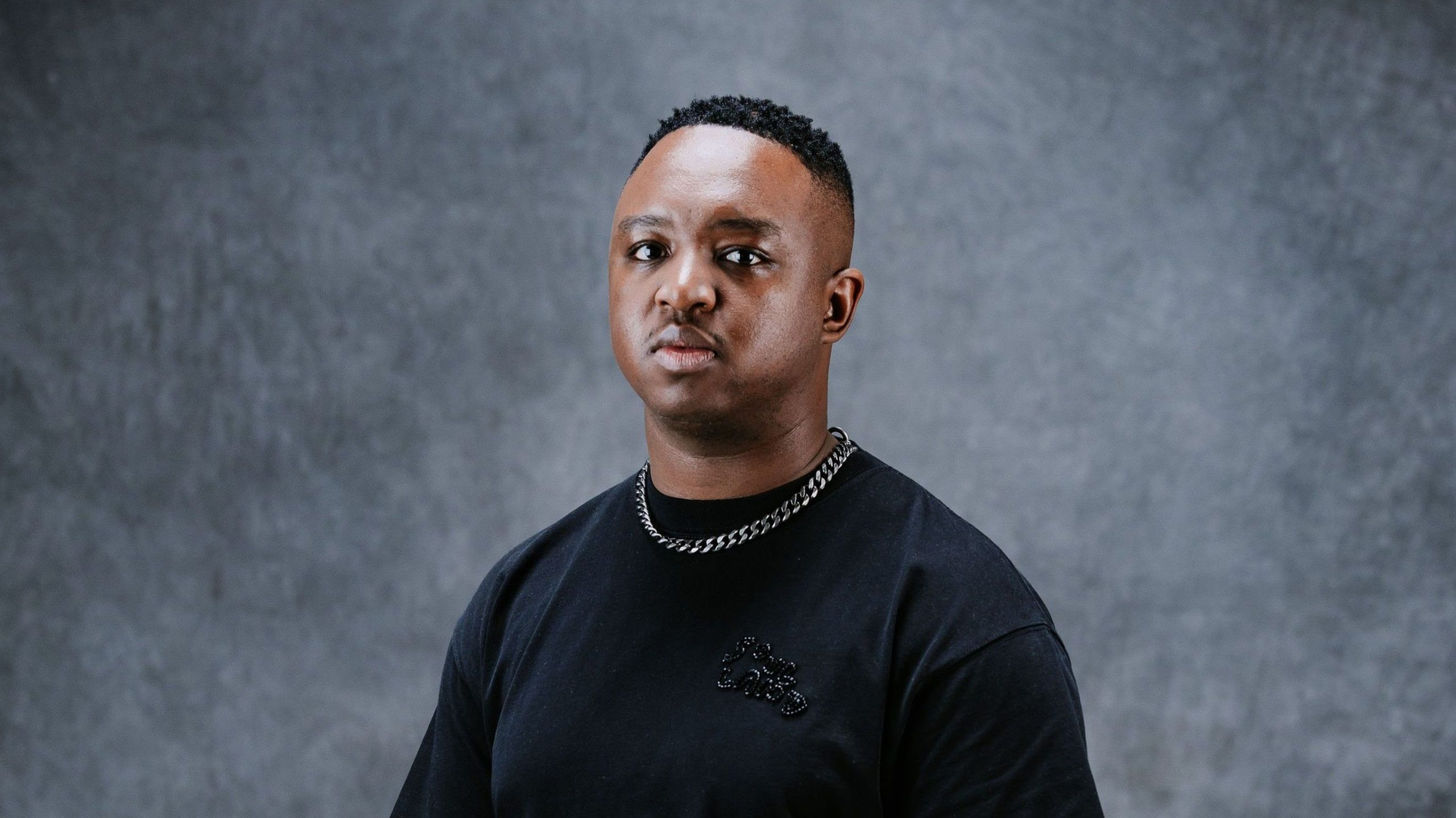 Person wearing black T-shirt and chain necklace.