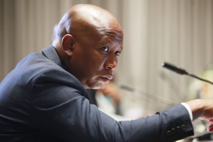 Person speaking at microphone during formal event.