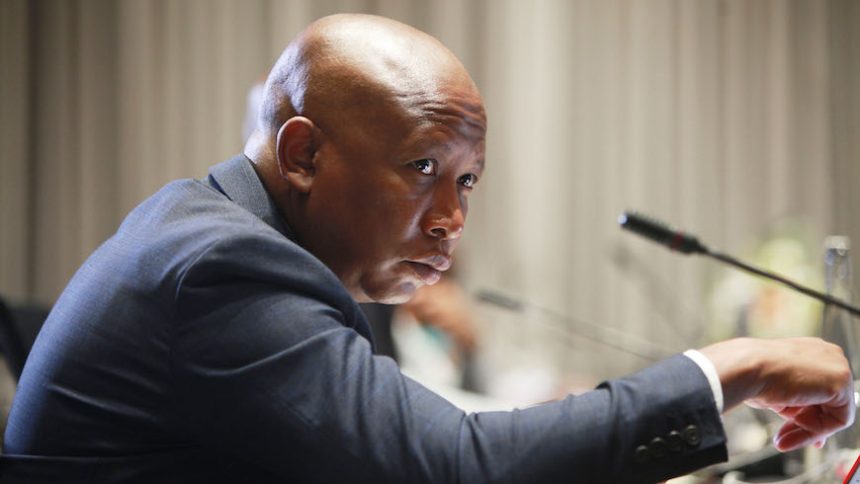 Person speaking at microphone during formal event.