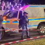 Police controlling nighttime crowd with barricade tape.