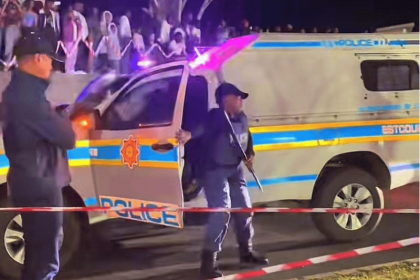 Police controlling nighttime crowd with barricade tape.