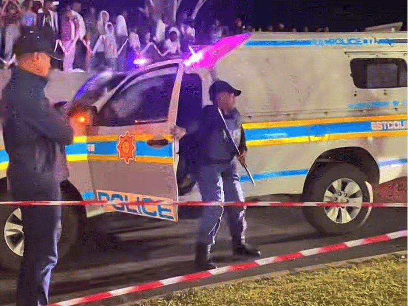 Police controlling nighttime crowd with barricade tape.