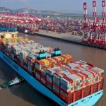 Cargo ship at busy shipping port and container cranes.